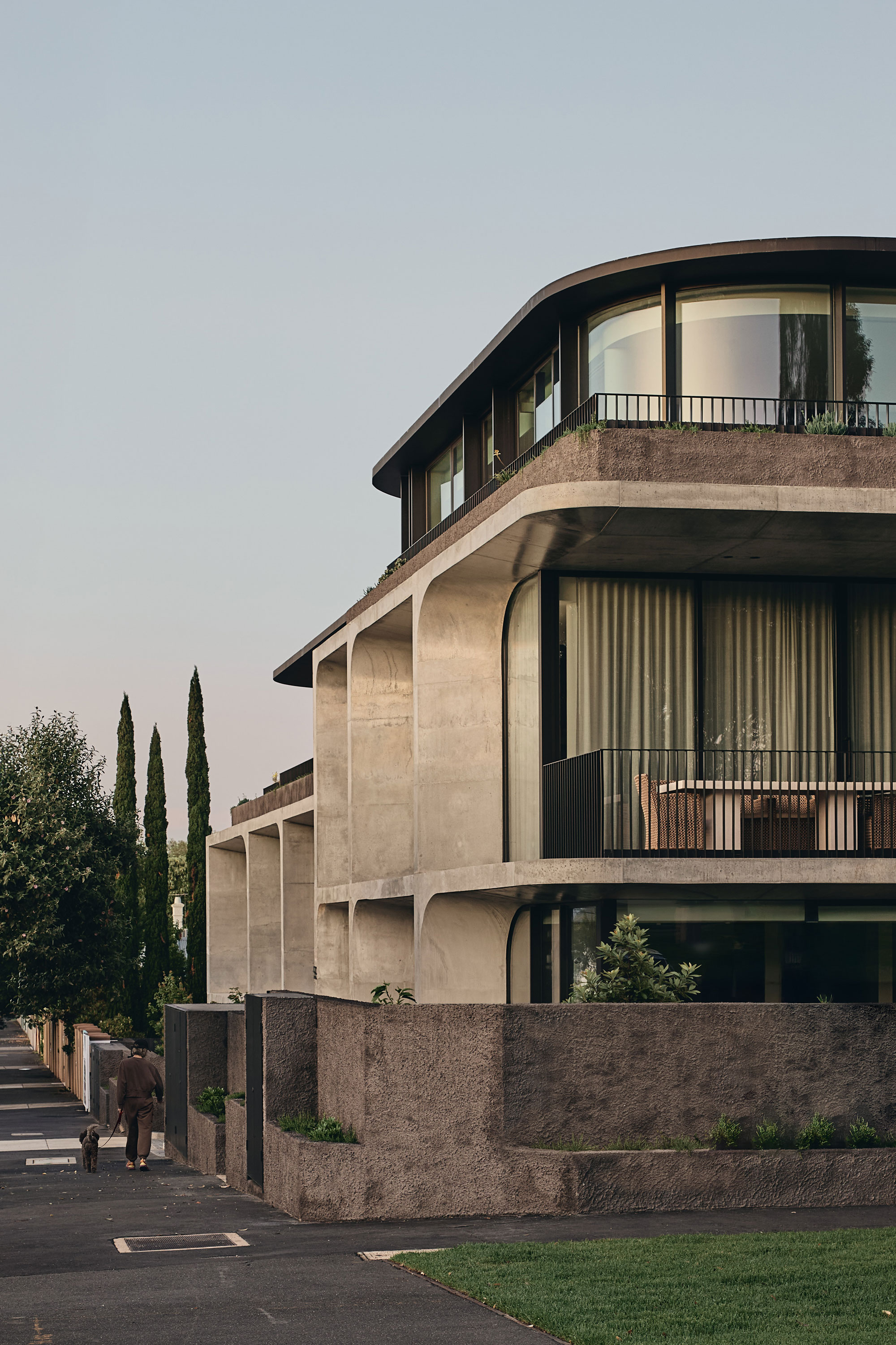 Morning sunlight hits the façade of modern architecture design with concrete detailing and curved glass windows.