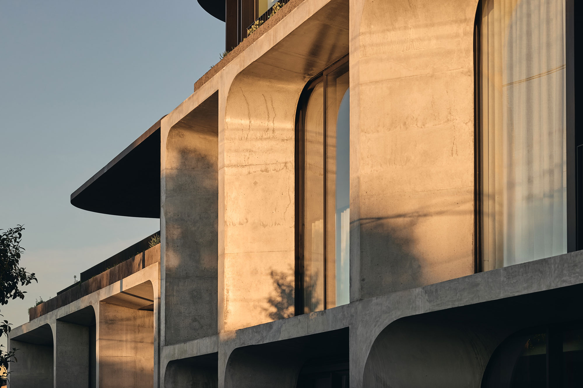 Warm sunlight casting shadows on modern multi-residential architectural building with concrete façade.