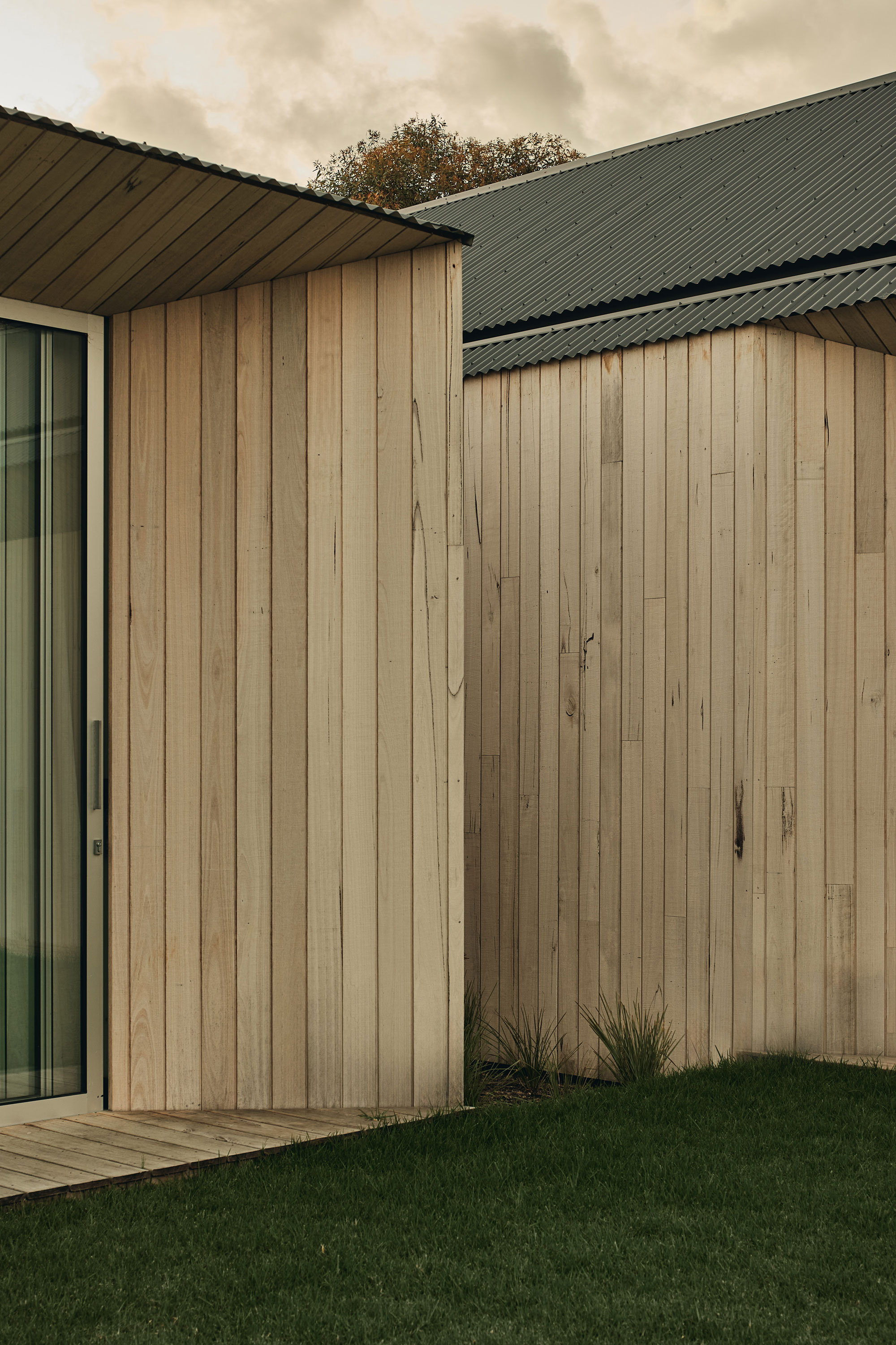 Timber clad house with architectural angles and lines contrasted by the lush green grass.