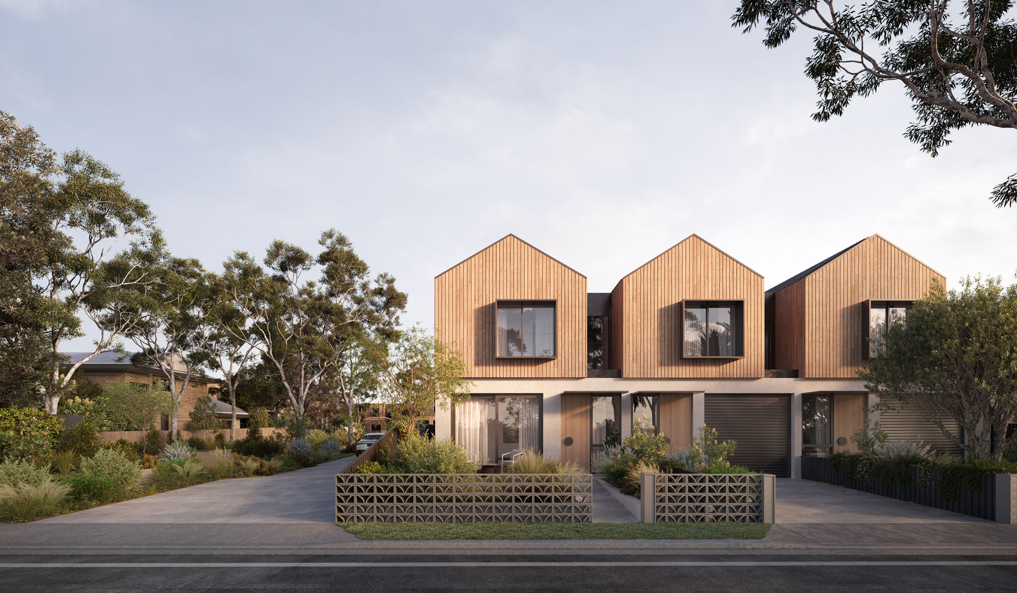 The entry for three double storey symmetrical townhouses with timber cladding, pitched roofs and lush landscaping.