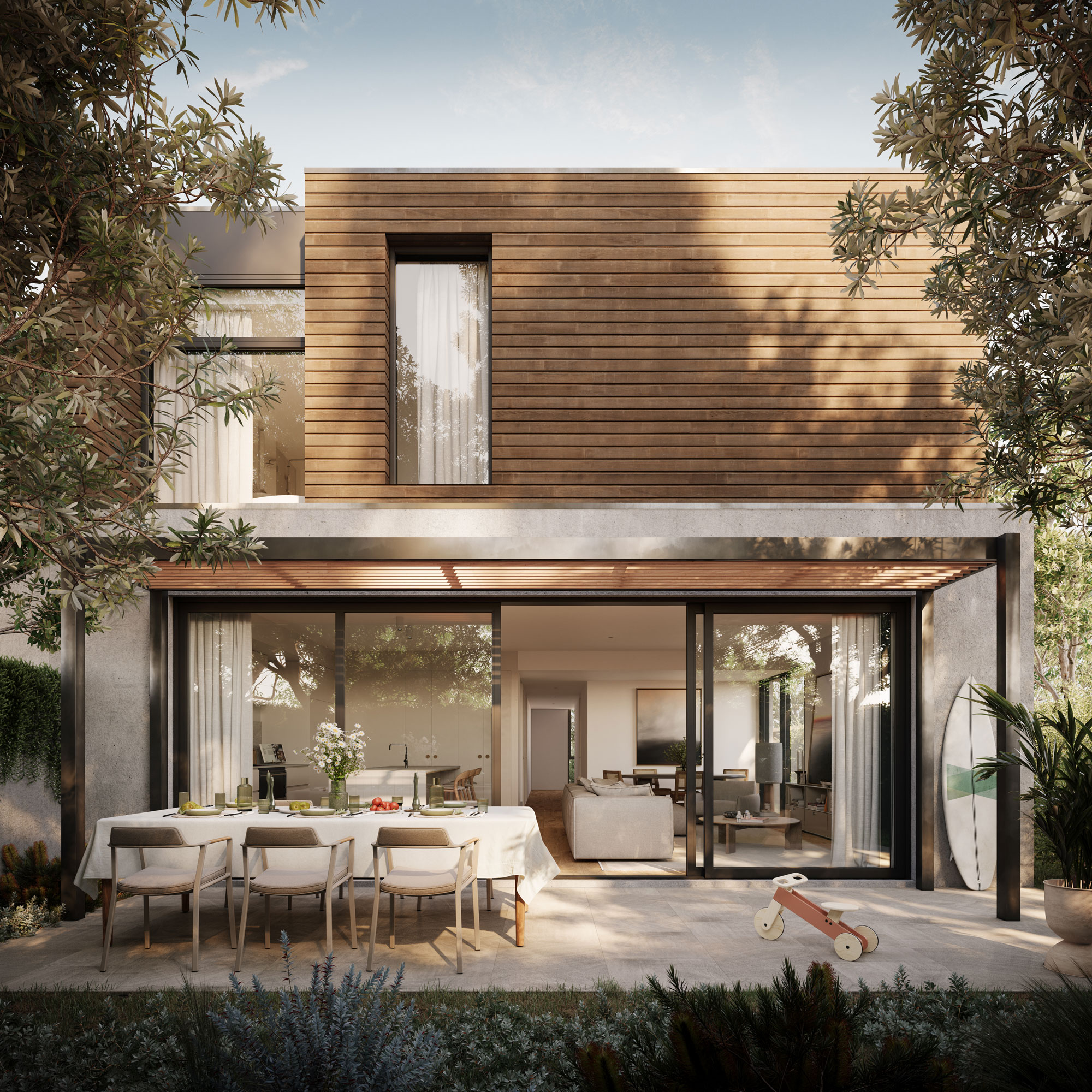 Soft sunlight casts shadows over outdoor entertaining area featuring double storey coastal townhouse with wood panels, lush landscaping and indoor / outdoor living spaces.