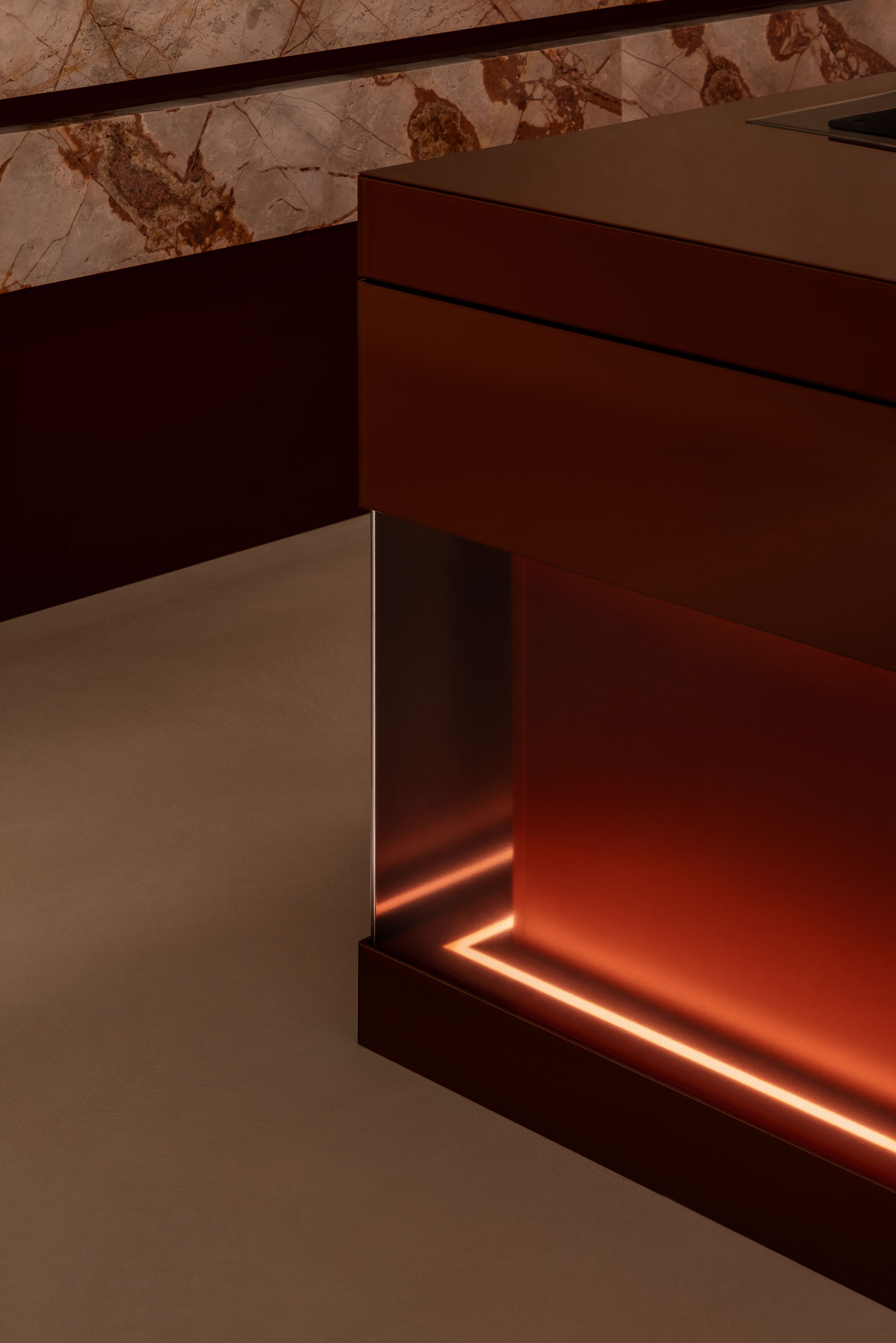 Corner detailing of kitchen island bench with warm tones and LED strip lighting, contrasted against soft polished concrete flooring.