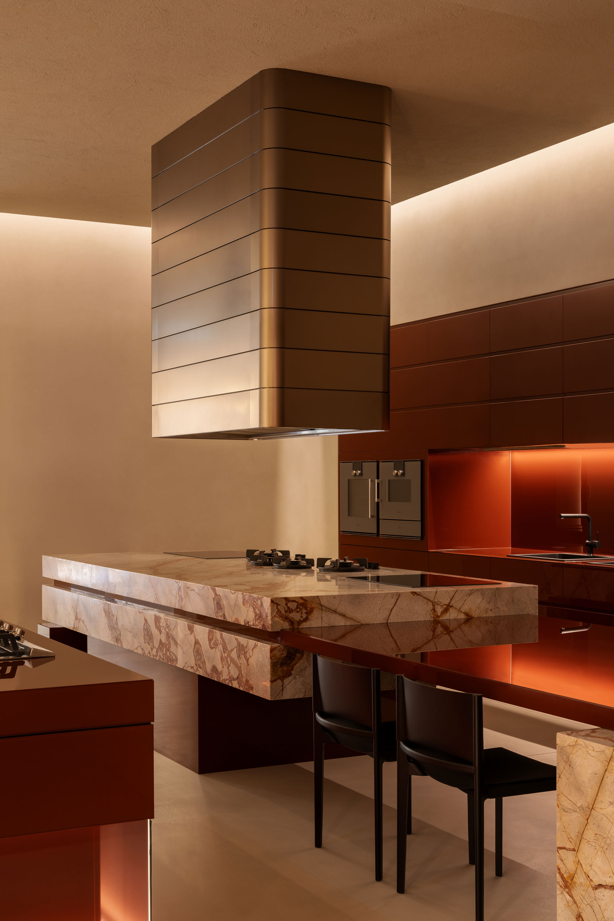 Luxurious kitchen with statement rangehood, contrasted with warm tone cabinetry and statement marble benchtops.