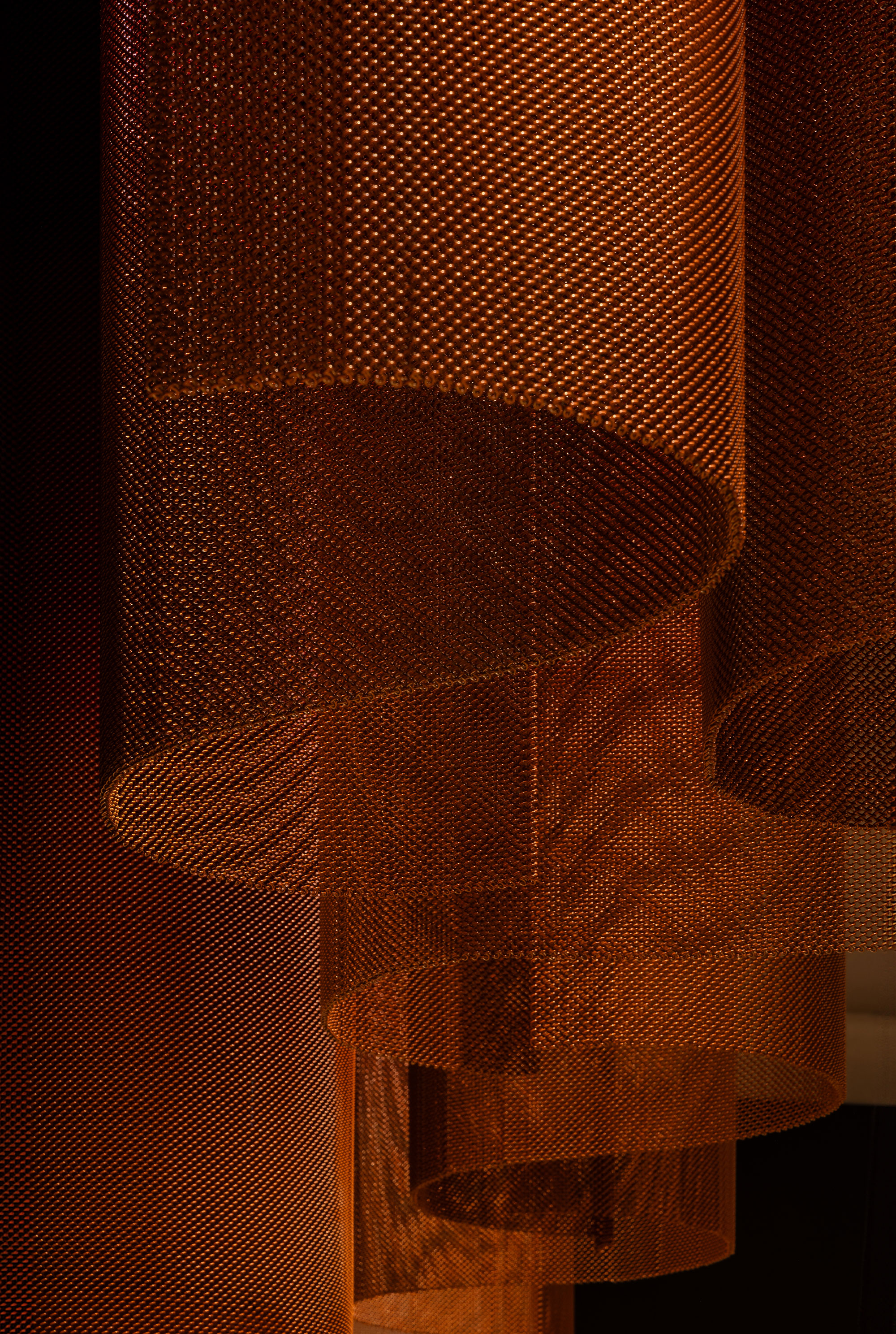 Close up of metal pendant light in a warm rust colour.