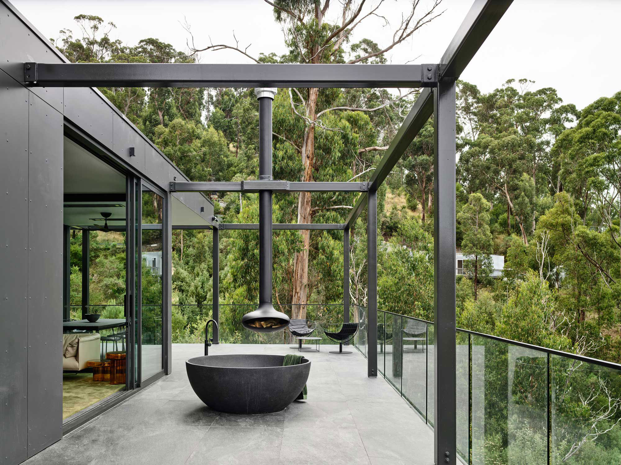 Large balcony with outdoor bath and fireplace overlook lush greenery.