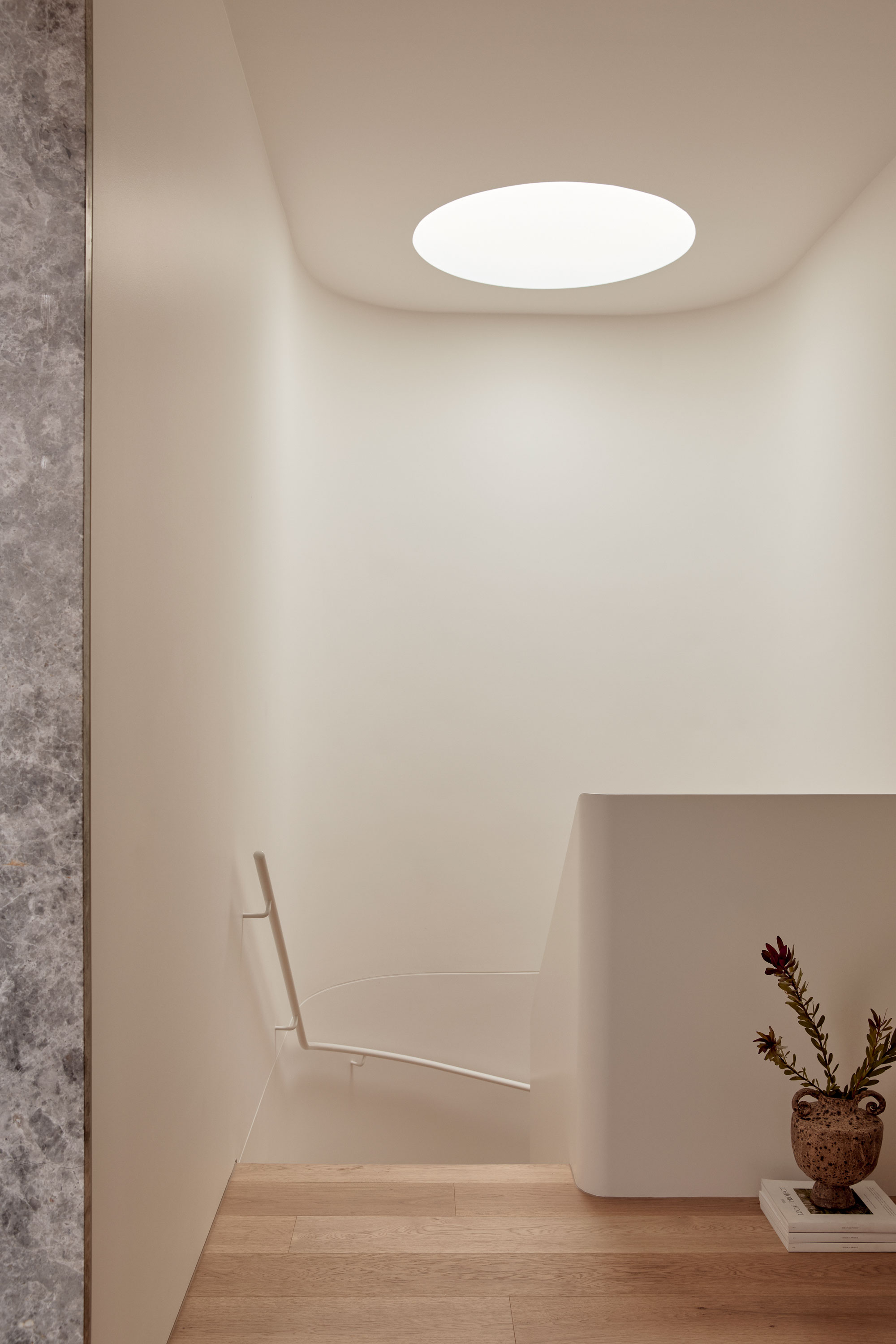 Light filled stairwell with round skylight, light timber floors and stone detailing.